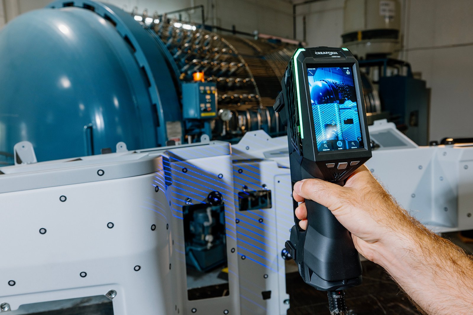 Creaform HandySCAN 3D EVO handheld scanner inspecting industrial metal parts with live touchscreen display.